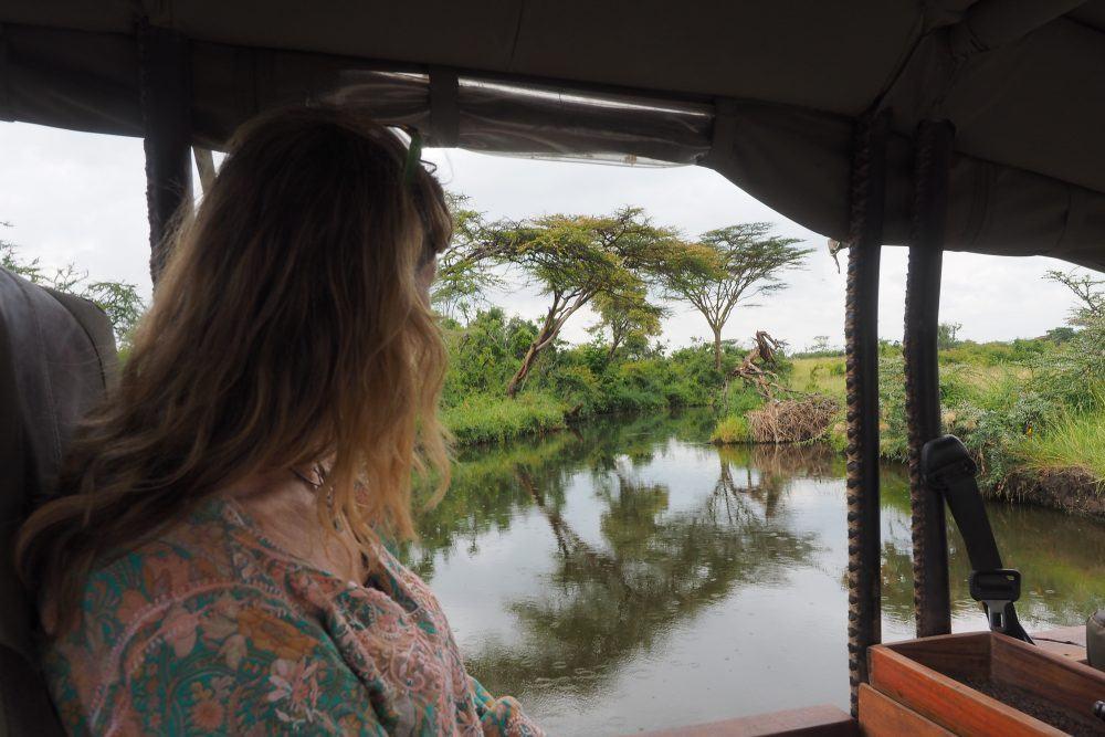 Woman sitting in safari jeep looking at river in Masai Mara, Kenya.