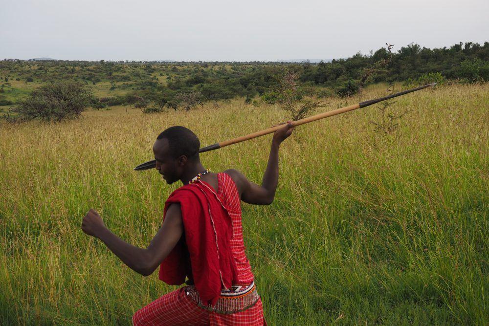 Maasai guide running and holding spear in Maasai Mara, Kenya.