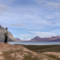 Man with rifle posing in arctic tundra landscape on Spitsbergen.