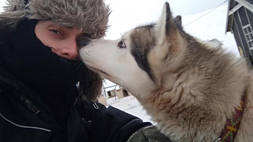 Woman being sniffed in the face by a husky dog on Svalbard.