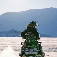 Person in Basecamp Explorer snowsuit with helmet driving a snowmobile in Spitsbergen.